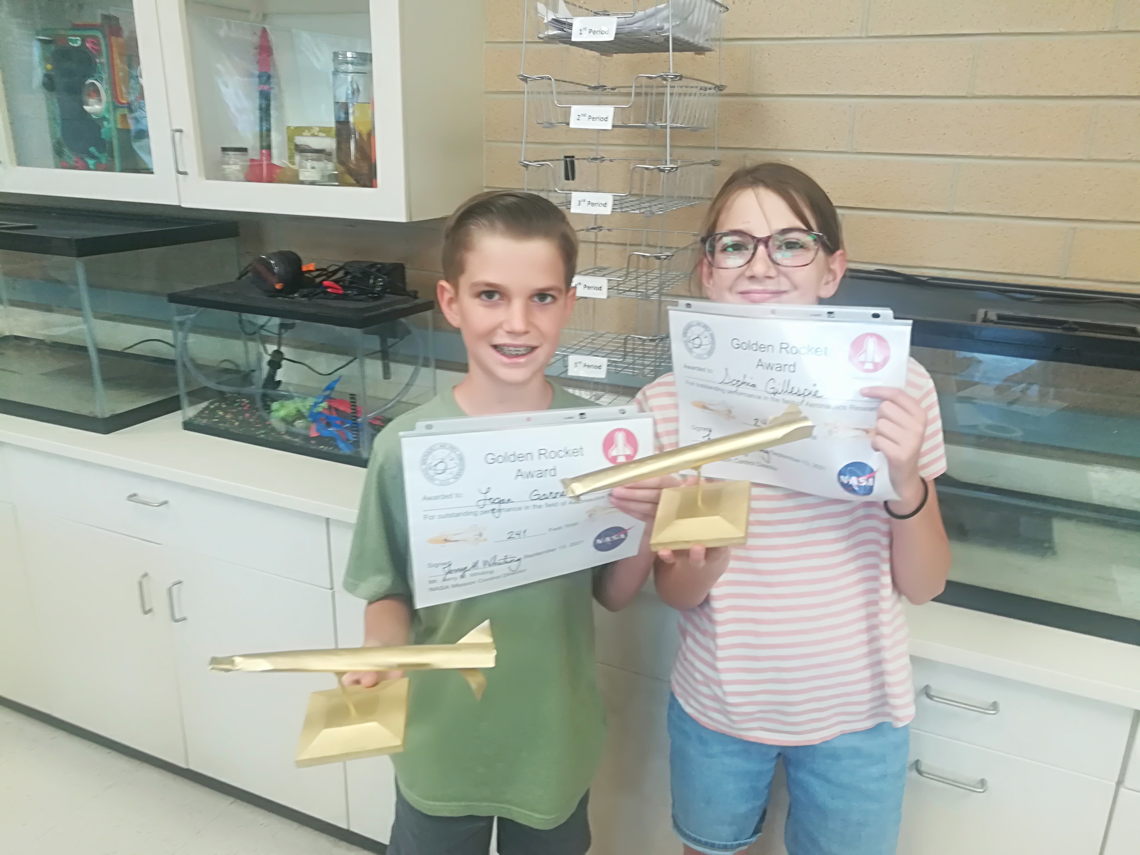 Students displaying their golden rocket trophies and certificates