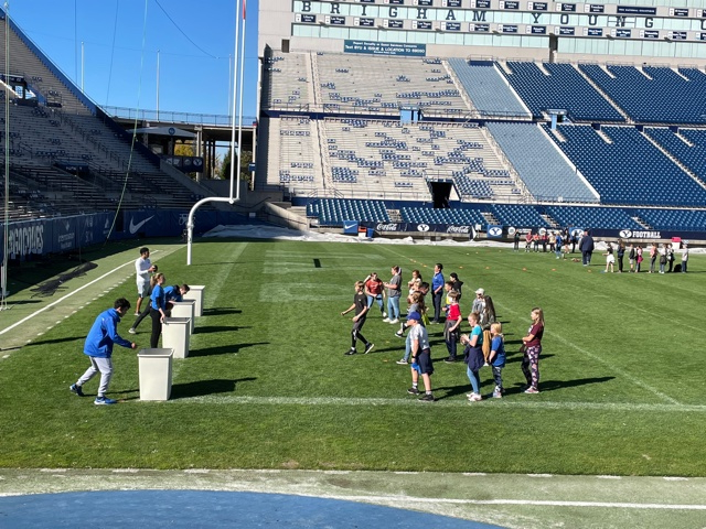 students playing football with BYU athletes