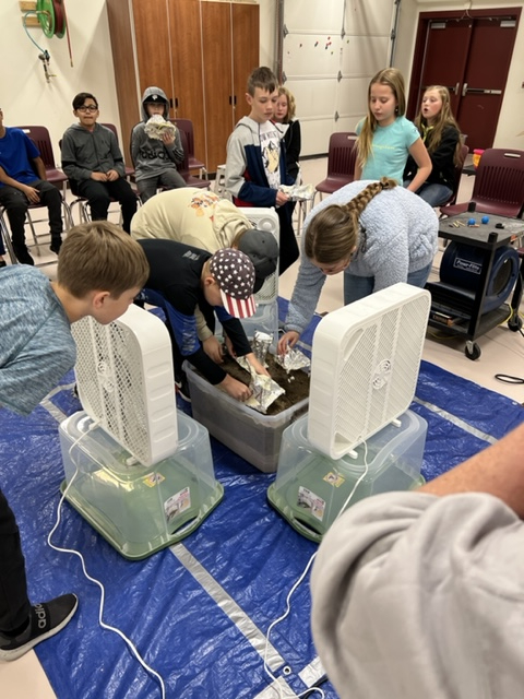 students using fans to simulate hurricanes on cardboard houses