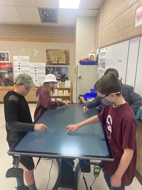 Four students all working on a flat screen computer panel