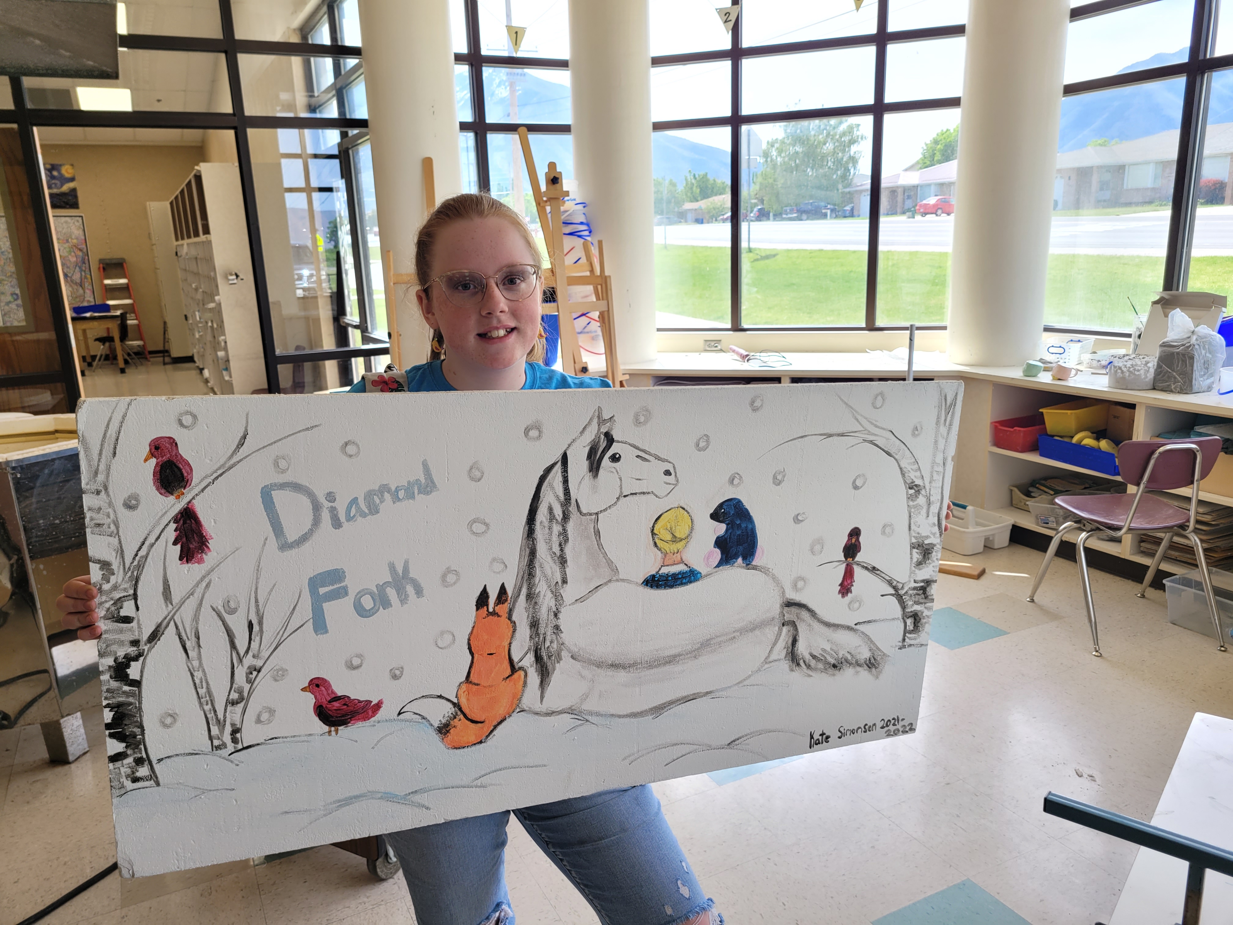 A student holds their ceiling tile art