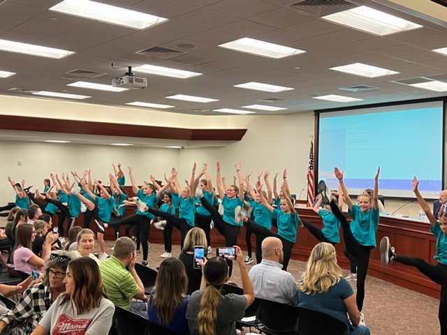 dance students doing a high kick at board meeting performance