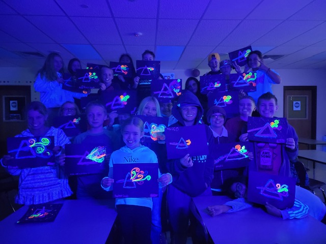 students in the dark holding up black light pictures
