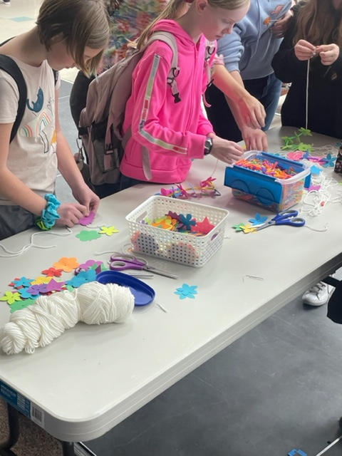 Students making leis at lunch with yarn, paper flowers, and string. 