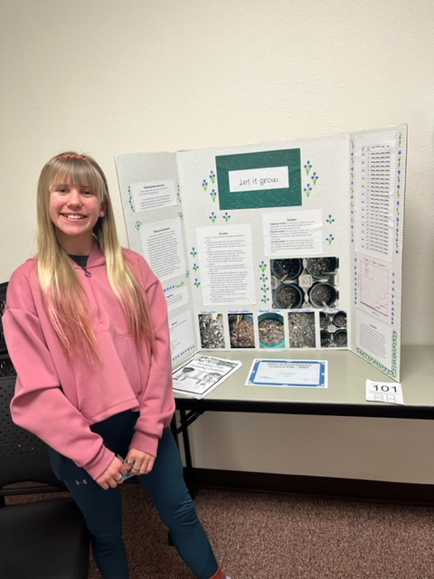 student standing by her science fair project