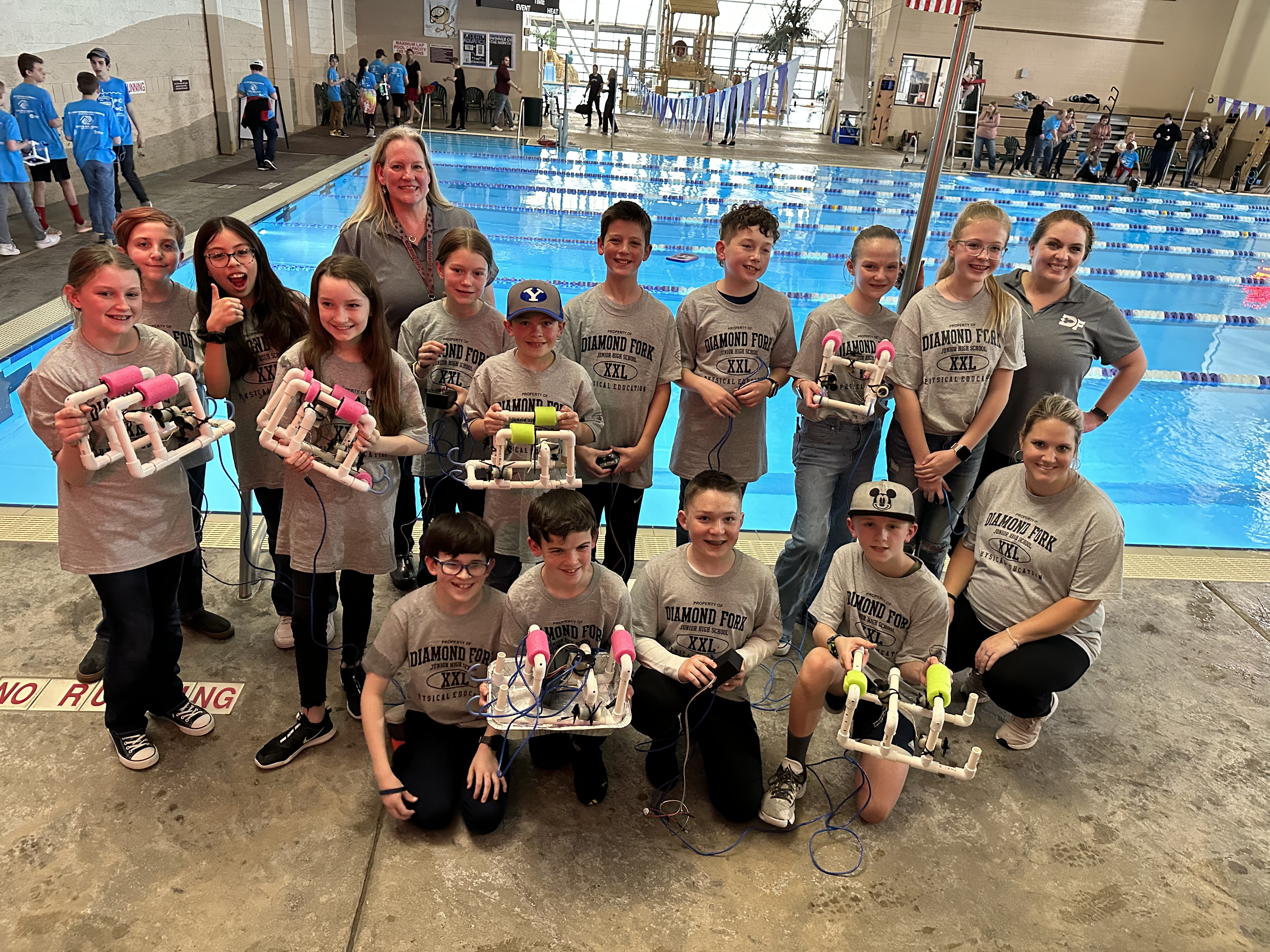 students holding their robots by the pool