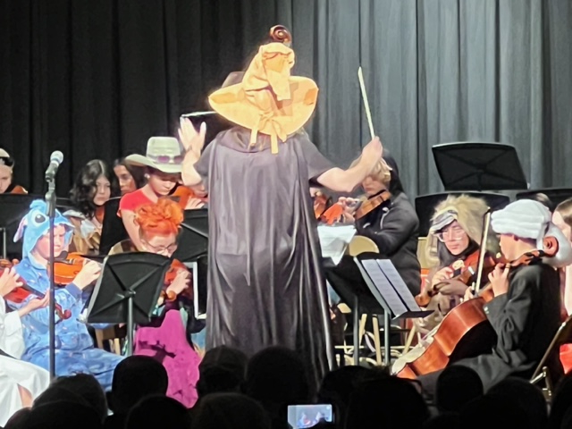 Students playing violins in Halloween costumes. 