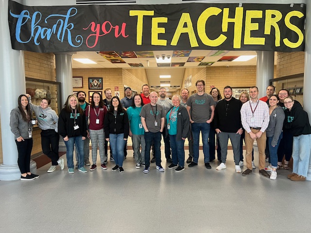 DFMS Faculty and Staff under a sign that says "Thank You Teachers"